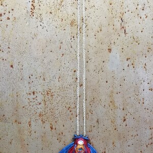 May include: A silver chain necklace with a blue and red moth pendant. The moth has a large, detailed eye with gold accents.