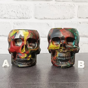 May include: Two colorful skull-shaped planters with swirling red, yellow, green, and black paint. The planters are labeled A and B.