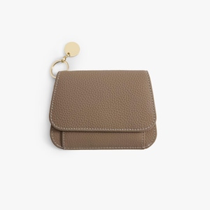 May include: A small, brown leather wallet with a gold key ring attached. The wallet has a textured surface and a flap closure.