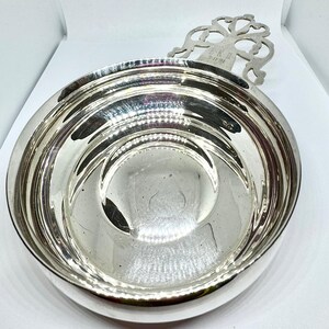 May include: A silver serving bowl with a decorative handle. The handle has a scroll design and the inscription "EK II 5191".
