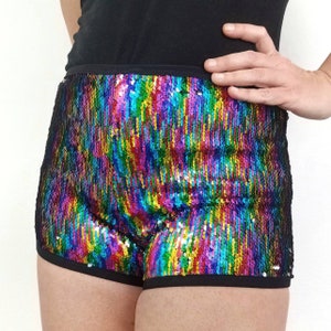 May include: Rainbow sequined shorts with a black waistband and trim. The shorts are made of iridescent sequins and have a high-waisted fit.