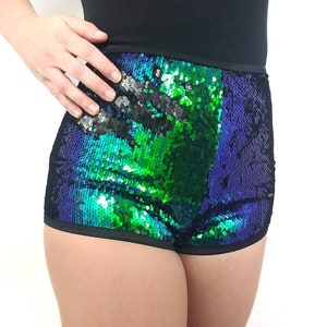 May include: Sequin shorts in a vibrant color scheme of green, blue, and black. The shorts have a high-waisted design with a black waistband and trim. The sequins create a shimmering effect, reflecting light.