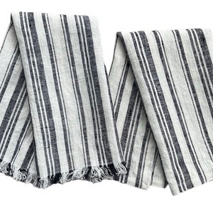 May include: Two white linen kitchen towels with black stripes and frayed edges.