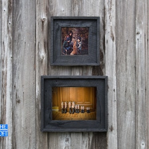 May include: Two black wood picture frames hanging on a wood wall. The top frame contains a photo of a family with a dog. The bottom frame contains a photo of a row of miniature boots.