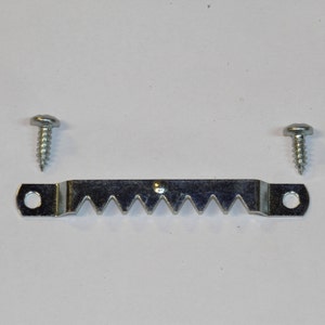 May include: A silver metal picture hanging hook with a serrated edge and two screws.