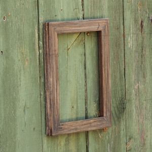 Puede incluir: Un marco de madera marrón con una abertura rectangular, montado en una pared de madera verde.