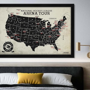 May include: A black and white map of the United States and Canada with red text showing the locations of National Hockey League arenas. The map is framed in black and hanging on a wall above a bed with yellow pillows.