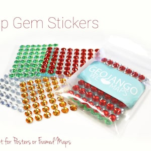 May include: Four bags of self-adhesive gem stickers in silver, green, red, and gold. The bags are labeled "GEOJANGO WE MAPS".