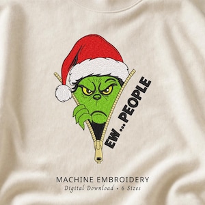 May include: A cream-colored sweatshirt featuring an embroidered design of a green character wearing a red and white Santa hat, peeking out from behind a gold zipper. The text "EW...PEOPLE" is embroidered in black next to the zipper.