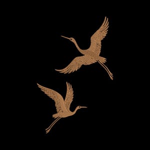 May include: Two embroidered crane birds in flight, rendered in a light brown thread color against a solid black background. Each bird is depicted with wings fully extended, long necks, and slender legs, showcasing detailed stitch patterns.