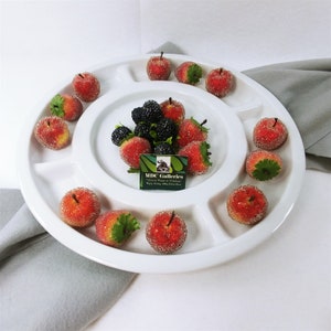 May include: White ceramic serving tray with multiple sections, filled with red and black faux fruit. The tray has a raised edge and a center section with a small card that reads "MDC Galleries".