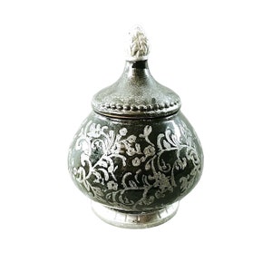 May include: A decorative ceramic jar with a silver floral design and a lid with a finial. The jar is dark green with silver accents.