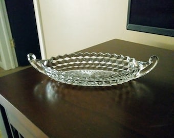 May include: A clear glass serving dish with two handles. The dish has a diamond pattern and is oval shaped.