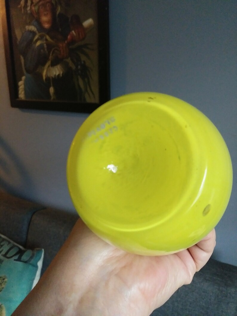 May include: A bright yellow glass vase with a round shape. The vase is empty and has a smooth, glossy finish.