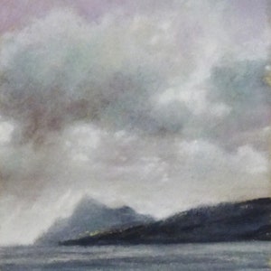 A view from the sea of the isles of Arran and Holy Isle, Scotland.  It is a grey day with rain clouds.