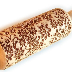 May include: A wooden rolling pin with a floral design carved into the surface. The rolling pin is made of light brown wood and has a natural finish.