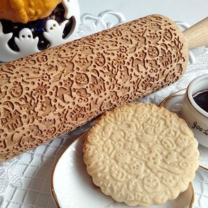 May include: A wooden rolling pin with a Halloween-themed design. The rolling pin is engraved with images of ghosts, pumpkins, bats, and other spooky symbols. A cookie with the same design is shown in the image.