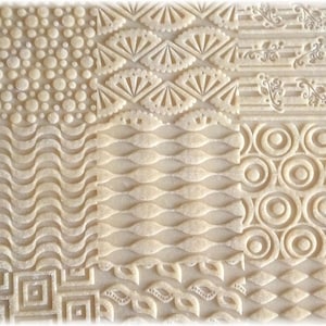 May include: A close-up of a sheet of dough with various patterns embossed into it. The patterns include circles, waves, leaves, and geometric shapes.