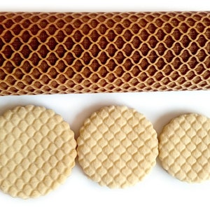 Puede incluir: Un rodillo de madera marr&oacute;n claro con un dise&ntilde;o de celos&iacute;a y tres galletas redondas con el mismo patr&oacute;n. El rodillo y las galletas est&aacute;n sobre un fondo blanco. El patr&oacute;n es un dise&ntilde;o de diamantes repetido.