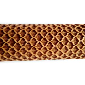 Puede incluir: Un rodillo de madera con un patr&oacute;n de celos&iacute;a decorativo tallado en la superficie de rodadura. Los mangos son lisos y de color claro, contrastando con la secci&oacute;n de rodadura m&aacute;s oscura y texturizada. Dise&ntilde;ado para hornear.