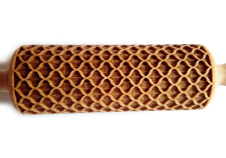 Puede incluir: Un rodillo de madera con un patr&oacute;n de celos&iacute;a decorativo tallado en la superficie de rodadura. Los mangos son lisos y de color claro, contrastando con la secci&oacute;n de rodadura m&aacute;s oscura y texturizada. Dise&ntilde;ado para hornear.