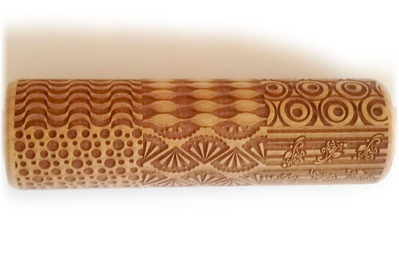 May include: A wooden rolling pin with a variety of engraved patterns, including waves, circles, dots, and a fan design. The rolling pin is brown and has a natural wood finish.