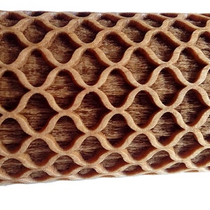 Puede incluir: Primer plano de un objeto de madera con un patr&oacute;n repetitivo en forma de onda. La madera tiene un tono marr&oacute;n c&aacute;lido y el patr&oacute;n est&aacute; tallado en la superficie, creando un efecto texturizado. El dise&ntilde;o es sim&eacute;trico y visualmente atractivo.