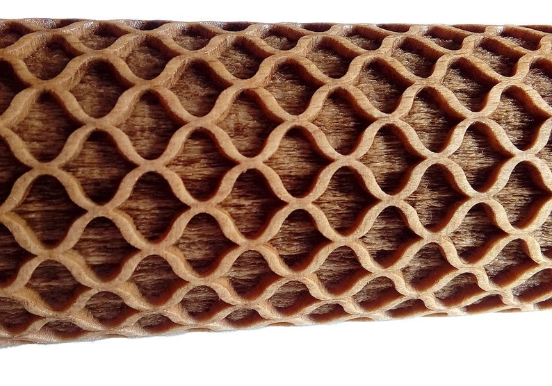 Puede incluir: Primer plano de un objeto de madera con un patr&oacute;n repetitivo en forma de onda. La madera tiene un tono marr&oacute;n c&aacute;lido y el patr&oacute;n est&aacute; tallado en la superficie, creando un efecto texturizado. El dise&ntilde;o es sim&eacute;trico y visualmente atractivo.