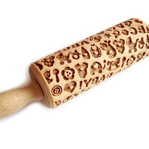 May include: A wooden rolling pin with a detailed design of baby-themed icons, including pacifiers, rattles, and onesies. The rolling pin is perfect for creating decorative patterns on cookies, fondant, or dough.