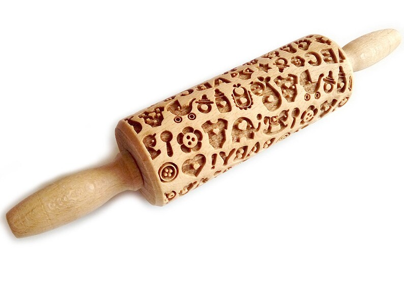May include: A wooden rolling pin with a detailed design of baby-themed icons, including pacifiers, rattles, and onesies. The rolling pin is perfect for creating decorative patterns on cookies, fondant, or dough.