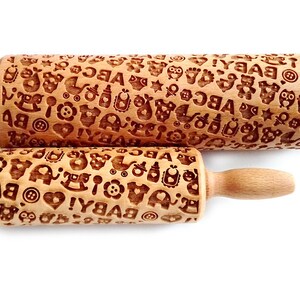 May include: Two wooden rolling pins with a baby theme. The rolling pins are engraved with letters, hearts, stars, and other baby-related designs. The larger rolling pin is 10 inches long and the smaller rolling pin is 6 inches long.