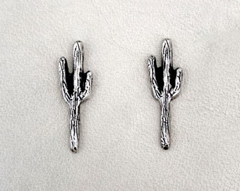 May include: A pair of silver cactus earrings. The earrings are small and delicate, and they feature a realistic cactus design.
