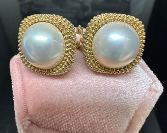 May include: A pair of gold-tone earrings with a large, white pearl in the center of each earring. The earrings are set in a square shape with a beaded border.