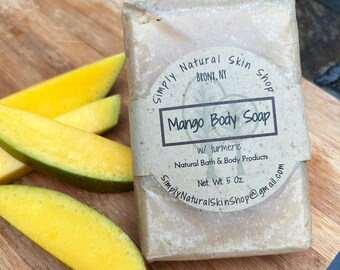 May include: A bar of mango body soap with turmeric, made by Simply Natural Skin Shop in the Bronx, NY. The soap is wrapped in brown paper and has a label with the company name and product information. The soap weighs 5 ounces and is made with natural bath and body products.