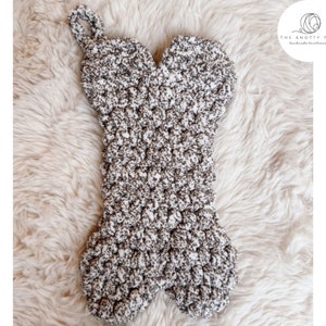 May include: A crocheted dog bone stocking in white and brown yarn. The stocking is shaped like a bone and has a loop at the top for hanging.