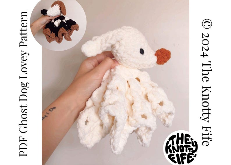 May include: A white crocheted ghost dog lovey with a brown nose and a white crocheted body. The lovey is being held by a hand with a tattoo on the wrist. The text "The Knotty Life" is visible in the bottom right corner of the image.