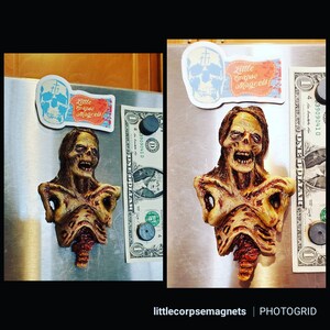 May include: A zombie-themed magnet with a detailed, decaying torso design. The magnet is brown, tan, and red, with a distressed appearance. A sticker with a skull and the text "Little Corpse Magnets" is also visible. The magnet is displayed on a metal surface.