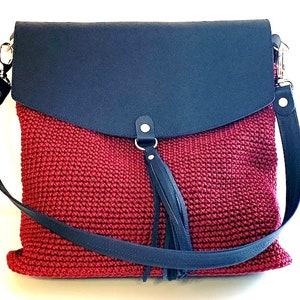 May include: A red crocheted bag with a dark blue leather flap and a long dark blue leather strap. The bag has a dark blue leather tassel.