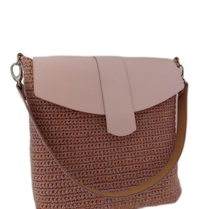 May include: A pink and brown crocheted shoulder bag with a leather flap and a brown strap.