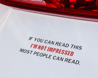 May include: White car bumper with a black and red sticker that reads "If you can read this I'm not impressed most people can read."