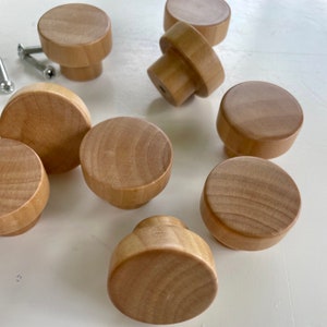 Könnte beinhalten: Neun Holzgriffe mit hellbrauner Oberfläche. Die Griffe sind rund und haben eine glatte Oberfläche. Sie sind perfekt, um jedem Einrichtungsprojekt einen Hauch von rustikalem Charme zu verleihen.