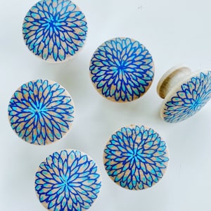 Może przedstawiać: Sześć drewnianych gałek z niebieskim i turkusowym wzorem kwiatowym. Gałki są okrągłe i mają gładką powierzchnię.