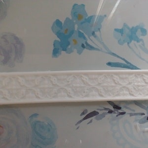 May include: White silicone mould with a raised design of a floral pattern. The mould is for making cake decorations or other edible items.
