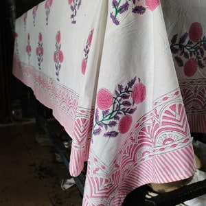 Puede incluir: Tela de algodón blanca con estampado floral rosa y morado. La tela tiene un borde de rayas rosa y blancas.