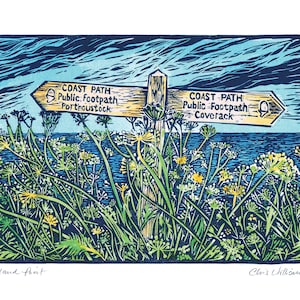 May include: A wooden signpost with two yellow signs pointing in opposite directions. The signs read "COAST PATH - Public Footpath Portnoustock" and "COAST PATH - Public Footpath Coverack". The signpost is in front of a blue body of water and green foliage.