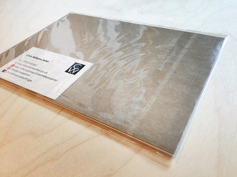 K&ouml;nnte beinhalten: Eine braune Papierkarte mit einer wei&szlig;en Visitenkarte darauf. Die Visitenkarte lautet "Chris Williams Artist" und enth&auml;lt Kontaktinformationen. Die Karte ist in durchsichtige Plastikfolie verpackt.