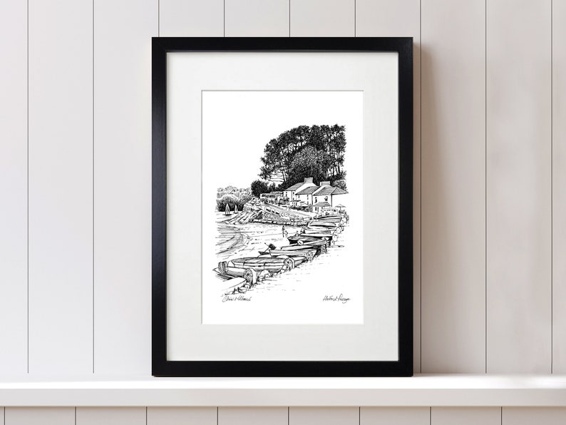 Puede incluir: Dibujo en tinta negra y blanca de un peque&ntilde;o pueblo con una fila de botes en la orilla. El dibujo est&aacute; enmarcado en un marco negro.