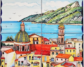 May include: Hand-painted ceramic tile set depicting a coastal Italian town. The artwork features a blue sea, green mountains, and colorful buildings with red and yellow roofs. The sky is light blue with white clouds and birds.