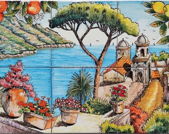 May include: A hand-painted ceramic tile mural depicting a picturesque Italian coastal scene. The mural features a vibrant blue sea, a lush green hillside, a charming village with white buildings, and a large pine tree. The scene is framed by potted flowers and a lemon tree.