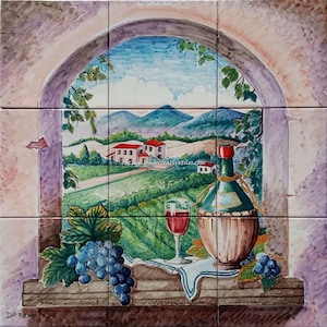May include: A hand-painted ceramic tile mural depicting a window view of a vineyard landscape with a bottle of wine, a glass of wine, and grapes. The tile mural is made up of 9 individual tiles.